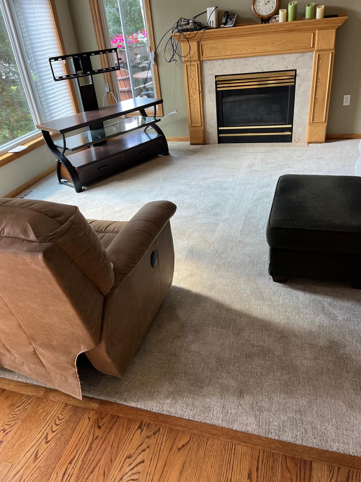 Light gray carpet installed in living room with fireplace and wood flooring transition.