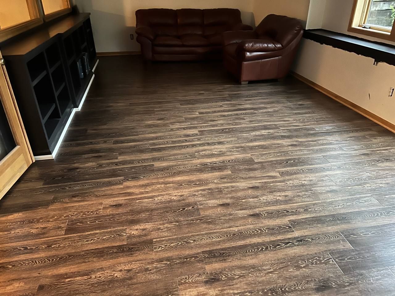 Living room with dark brown and gray plank LVP flooring installed in a glue-down method.