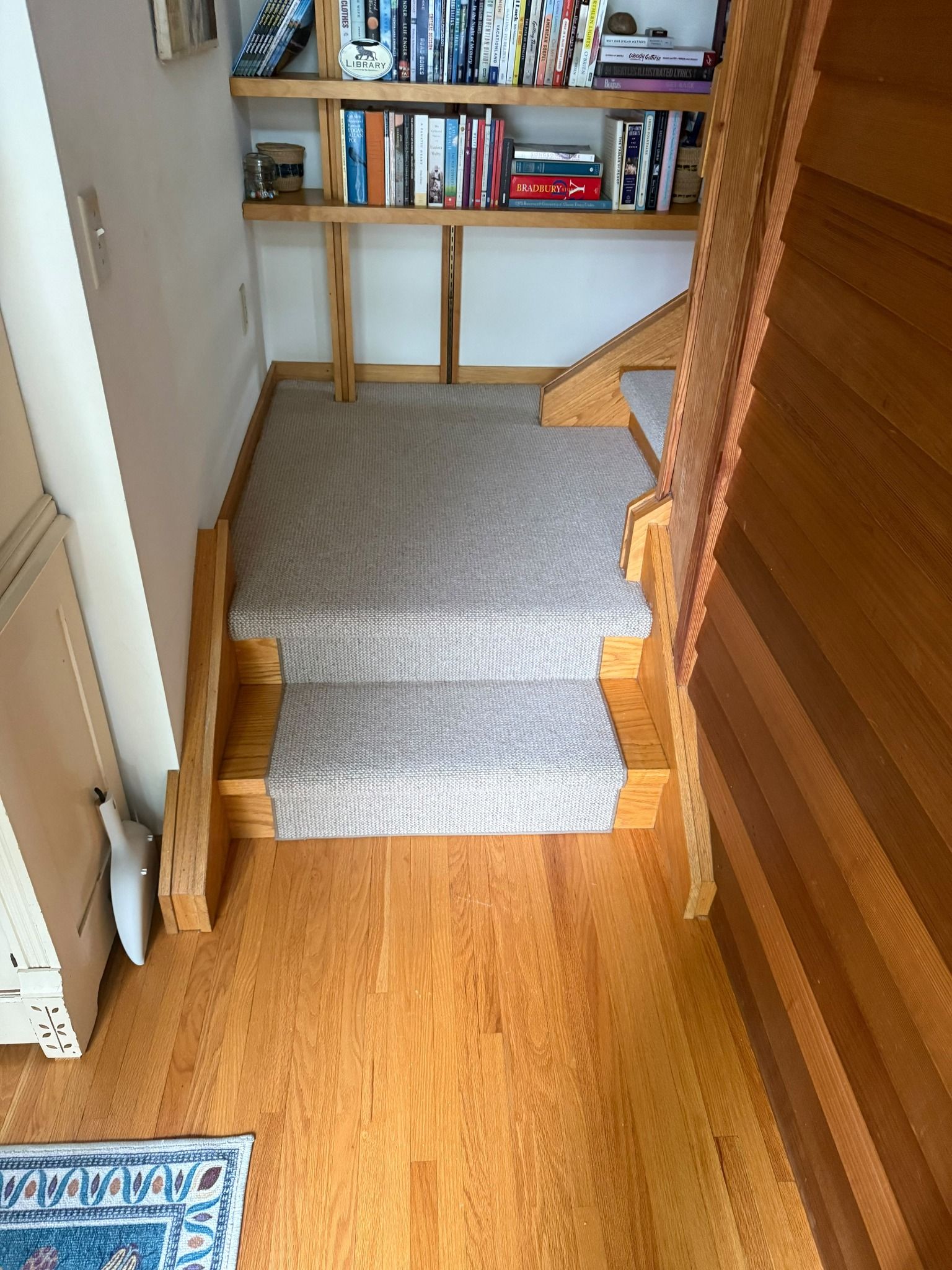 Gray carpet stair runner with wood borders installed on residential staircase.