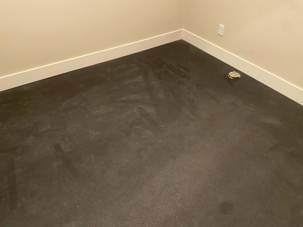 Dark LVP flooring installed in an empty room with white baseboards and beige walls.
