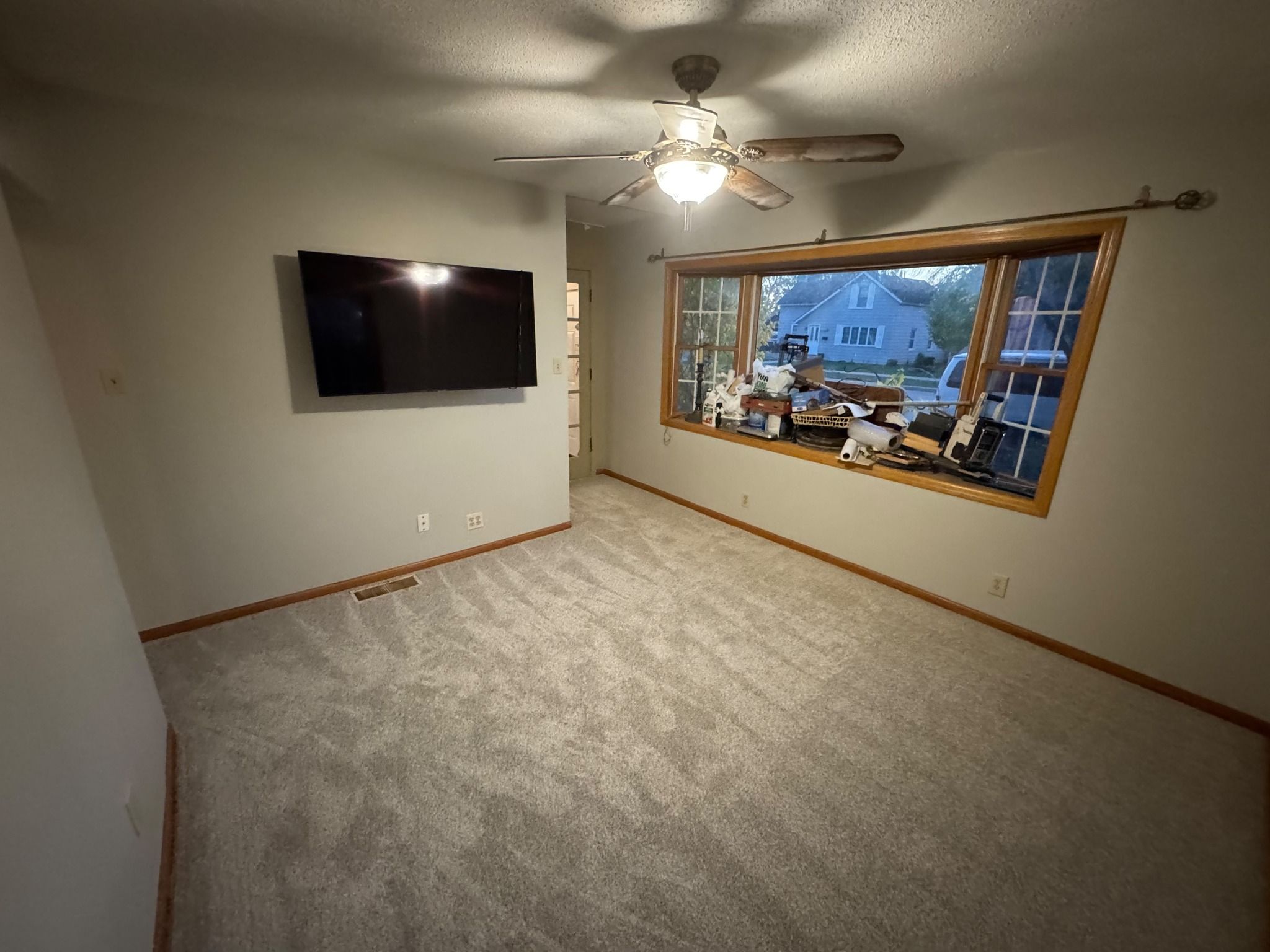 Living room with new light gray carpet and wood-trimmed baseboards.