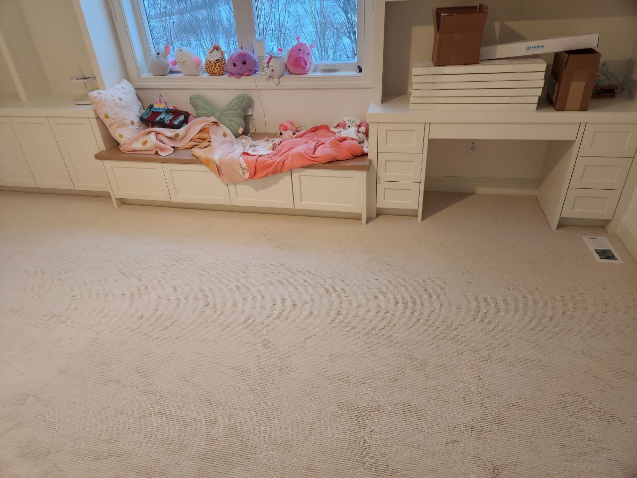 Light beige carpet installed in a bedroom with white built-in furniture and large windows.