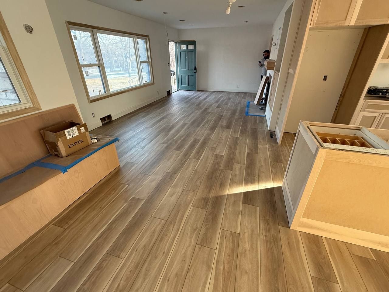 Newly installed LVP flooring in plank pattern throughout an open living space with natural light from large windows.