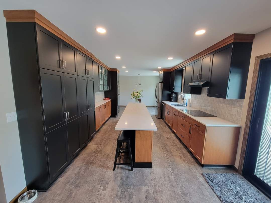 Kitchen with brown wood-look LVP flooring, island with seating, and black cabinetry.
