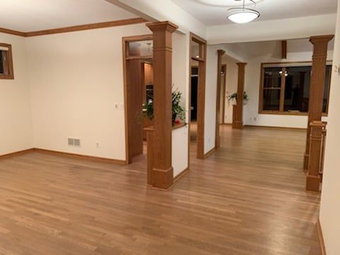 Refinished white oak hardwood flooring in a basement space with support columns and cream-colored walls.