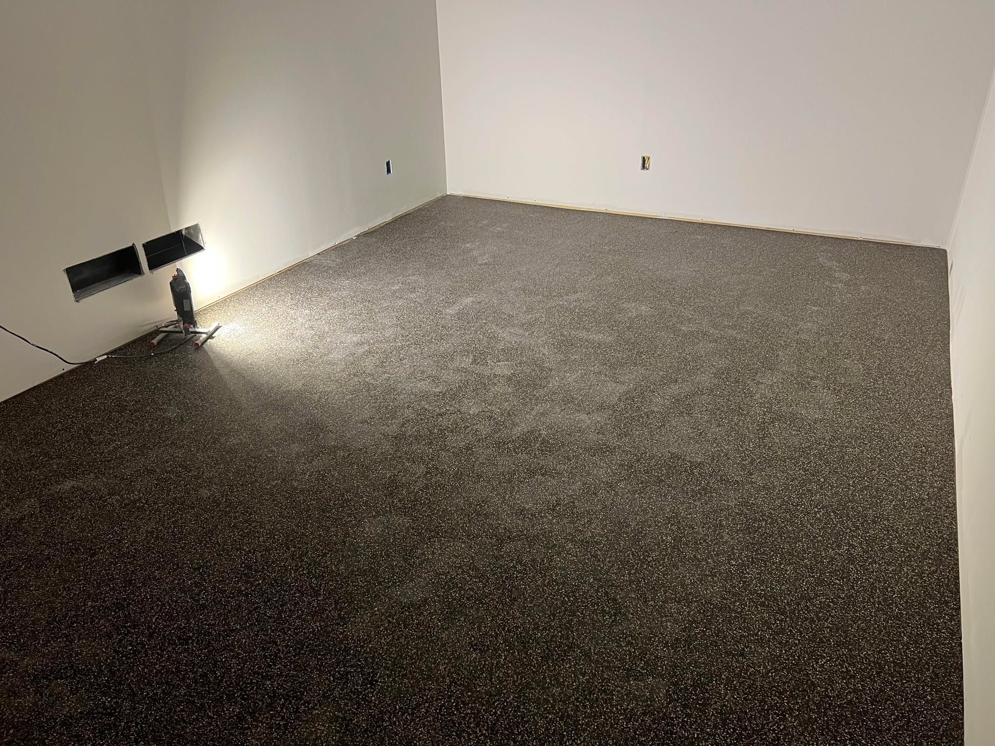 Empty bedroom with newly installed dark gray LVP flooring and white walls.
