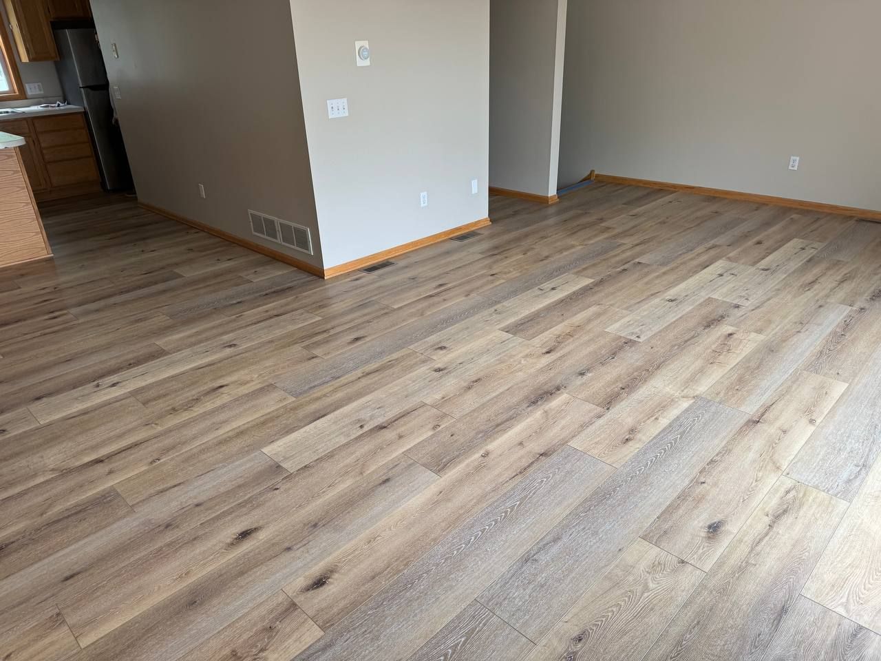 Living room with tan and gray wood-look LVP planks installed in a staggered pattern.