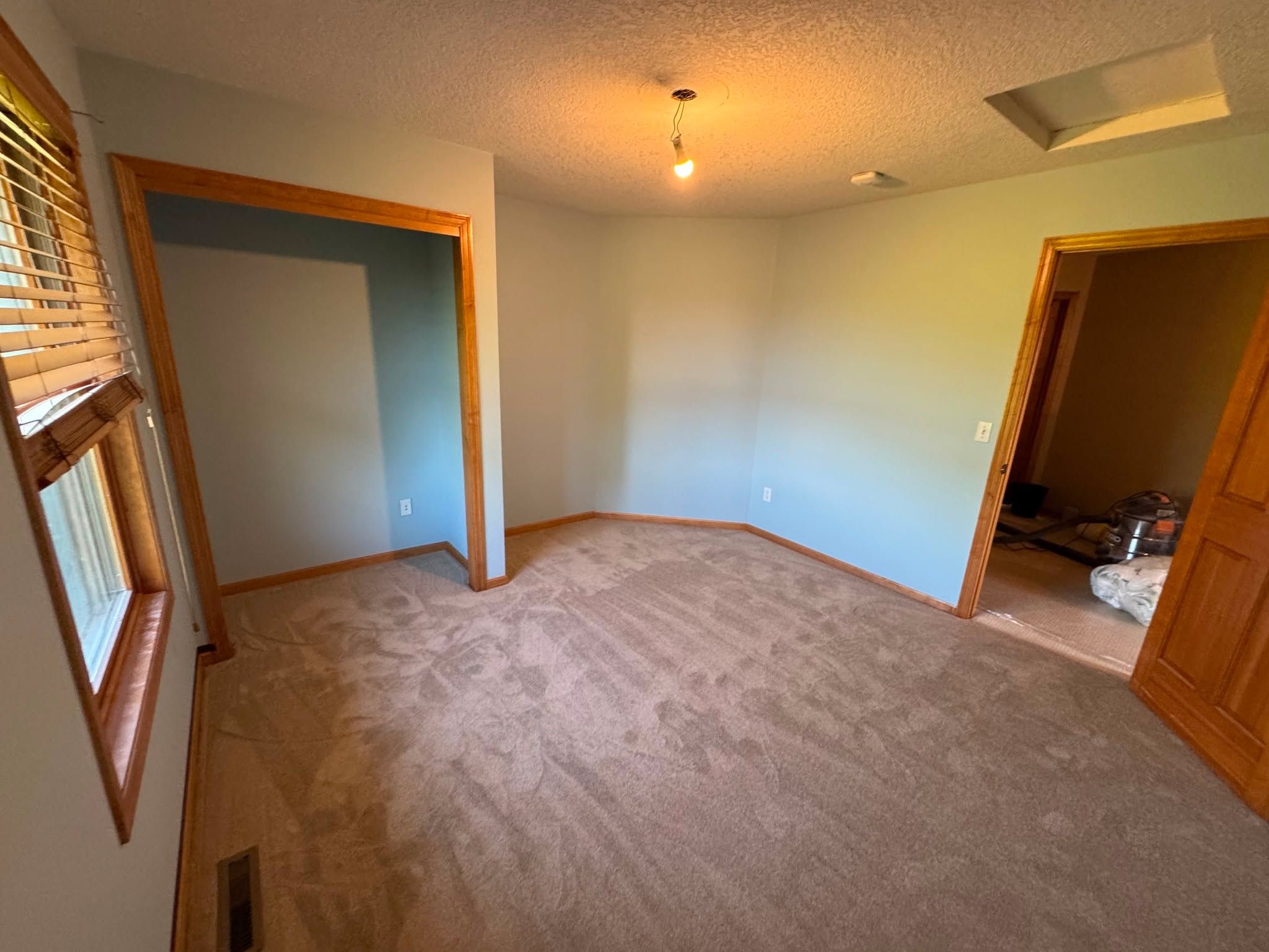 Bedroom with new medium brown carpet and wood door frames.