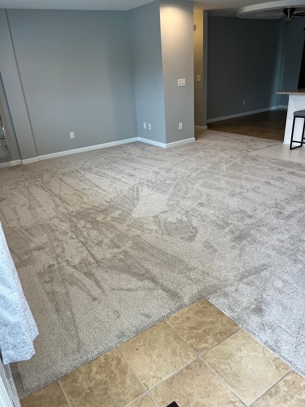 Living room with gray and tan patterned carpet in a newly renovated space with light blue walls.