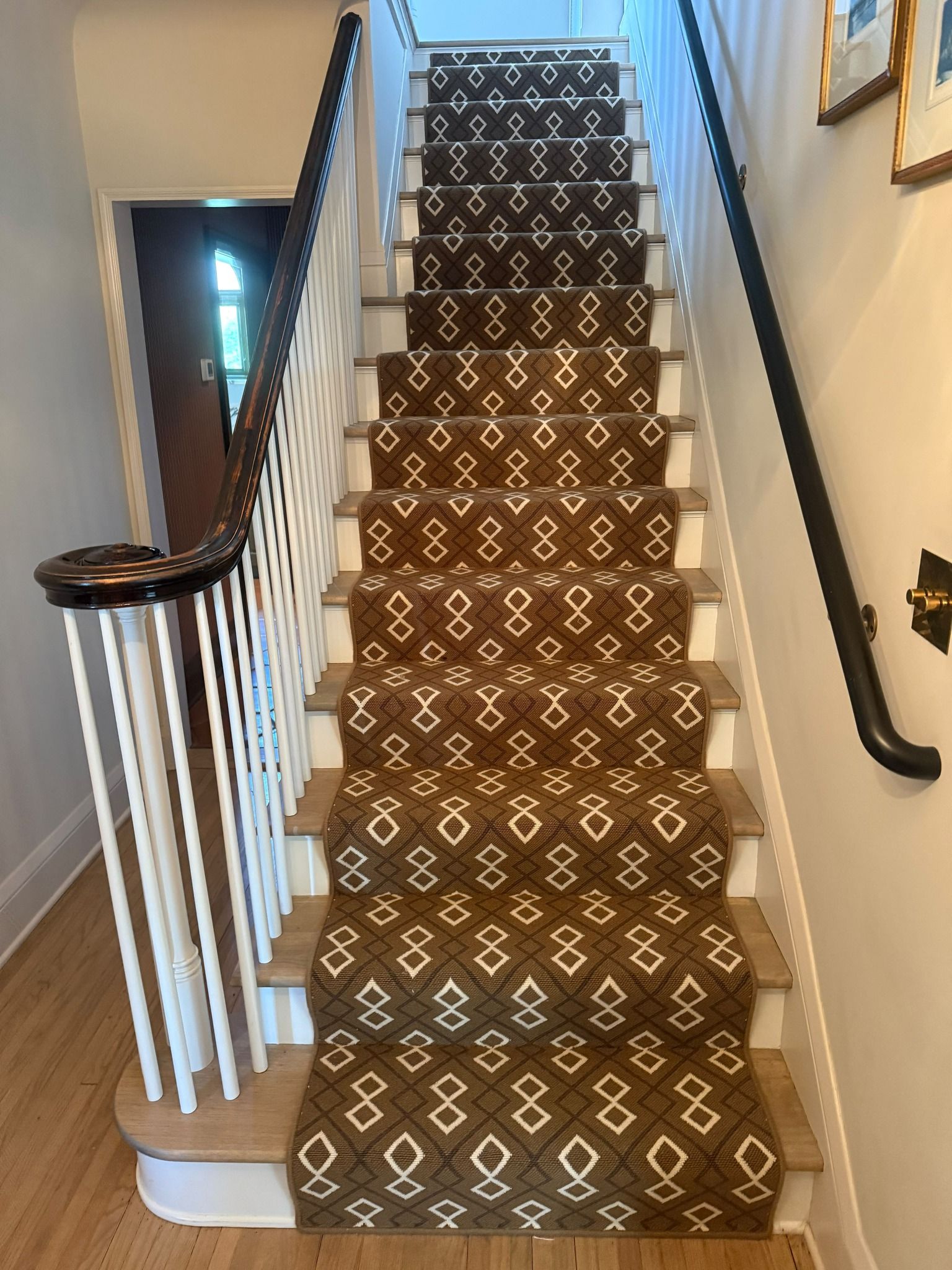 Carpeted staircase with a geometric diamond patterned runner and wood treads.