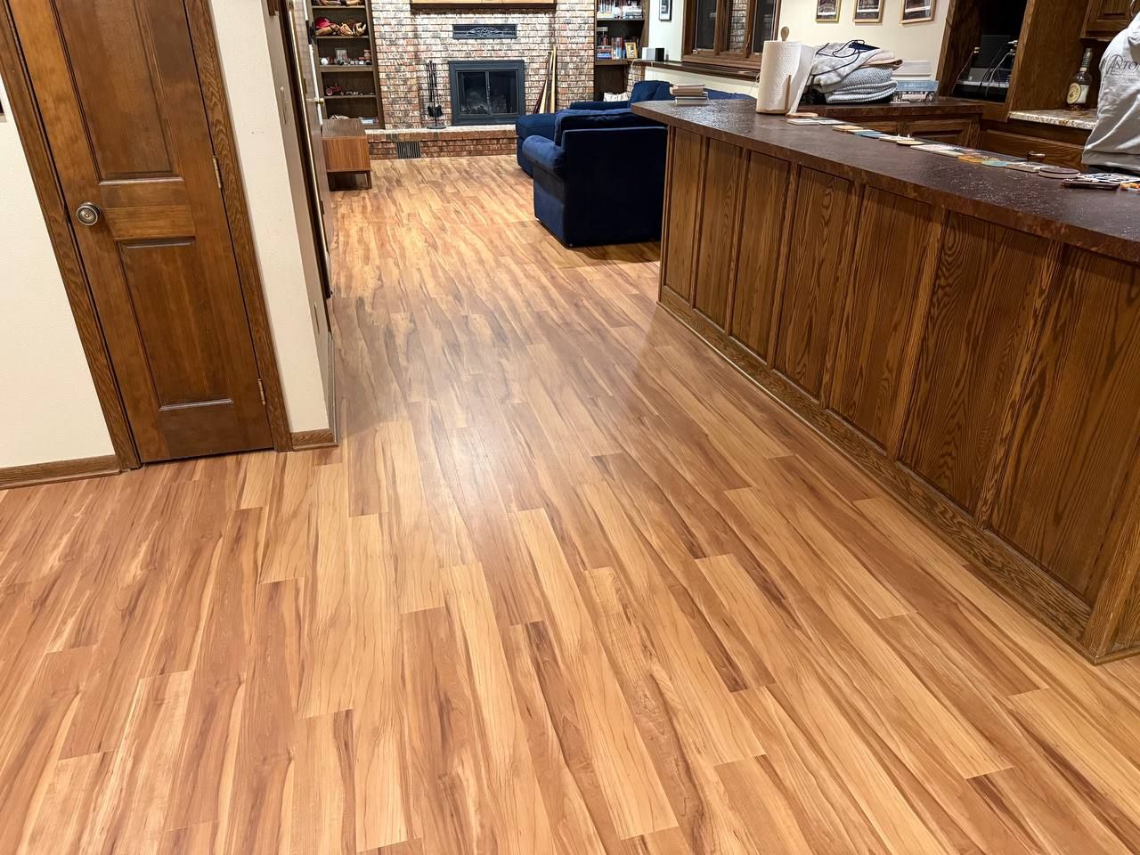 Living room with tan and brown wood-grain luxury vinyl plank flooring installed in a staggered plank pattern.