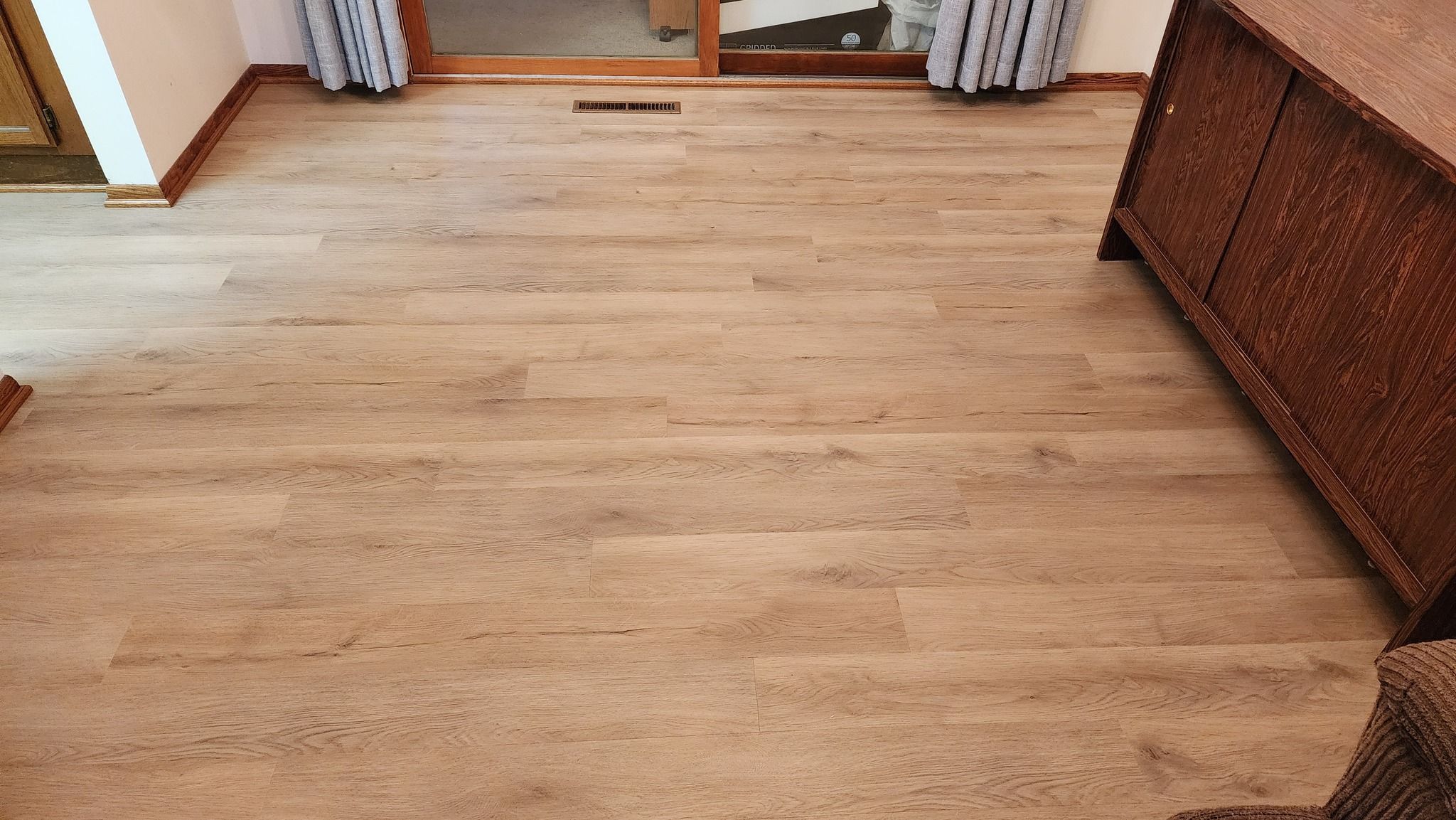 Light tan luxury vinyl plank flooring with wood grain texture installed in a bedroom.