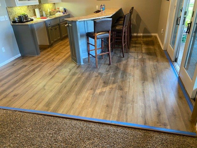 LVP plank flooring with wood grain pattern installed in kitchen and dining area with island and bar seating.