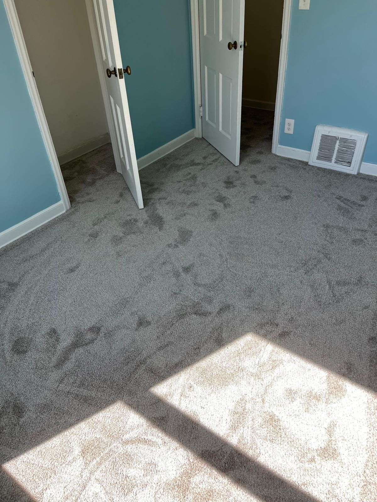 Gray carpet installed in bedroom with teal walls and white trim closet doors.