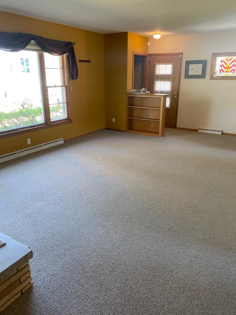 Newly installed light beige wool carpet in an open living room with yellow walls and wooden furniture.