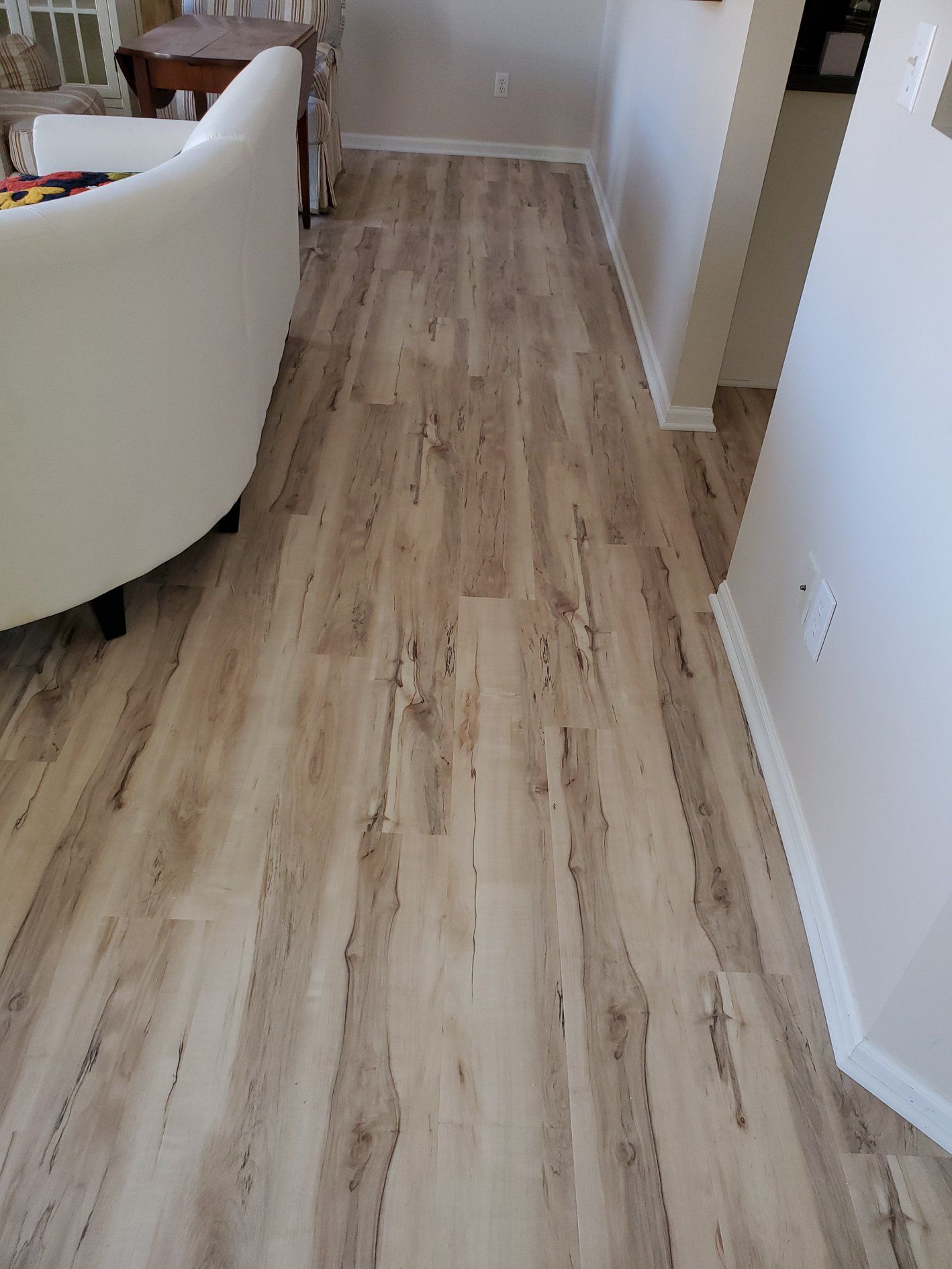 Hallway with light tan and gray plank flooring extending from living area.