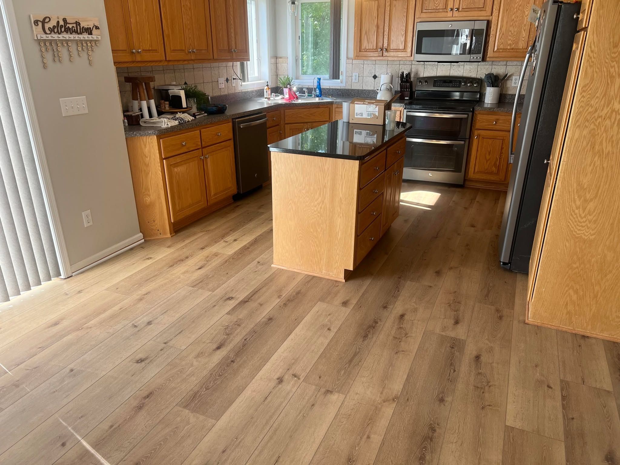 Kitchen with light to medium brown wood-look LVP flooring and wooden cabinets.