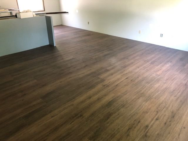 Medium brown wood-look LVP planks installed in an open living space with kitchen counter visible.