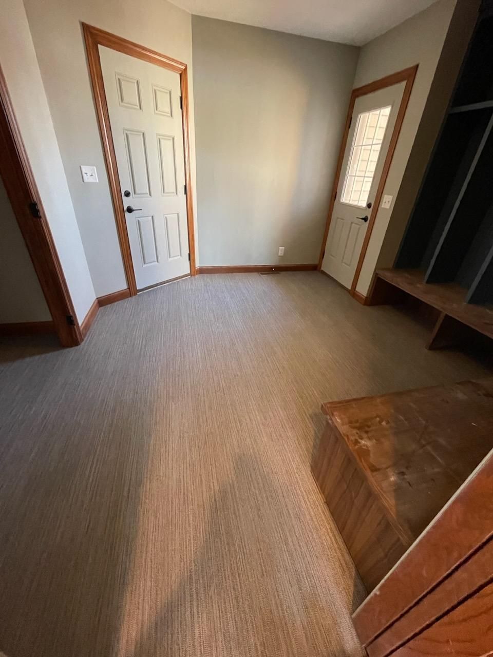 Bedroom with new gray carpet, wood door frames, and white panel doors.