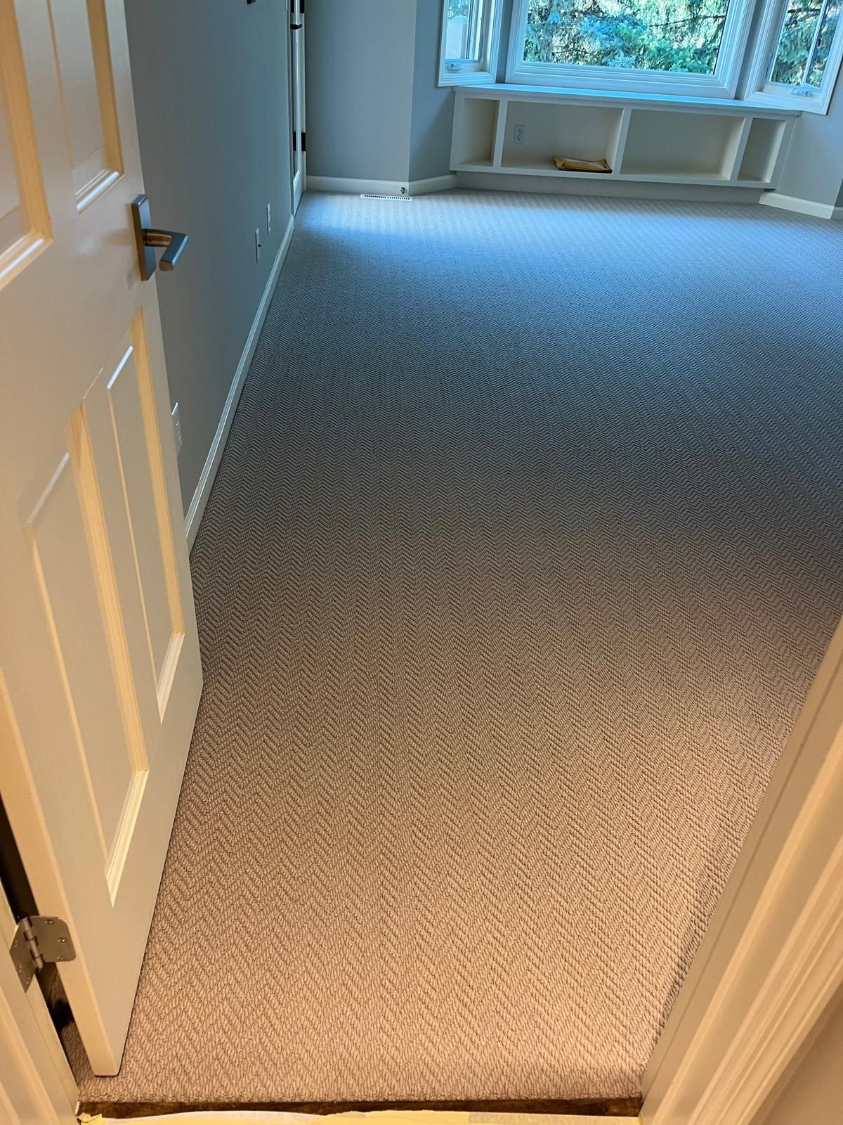 New herringbone patterned carpet installed in a bedroom with gray and tan tones.