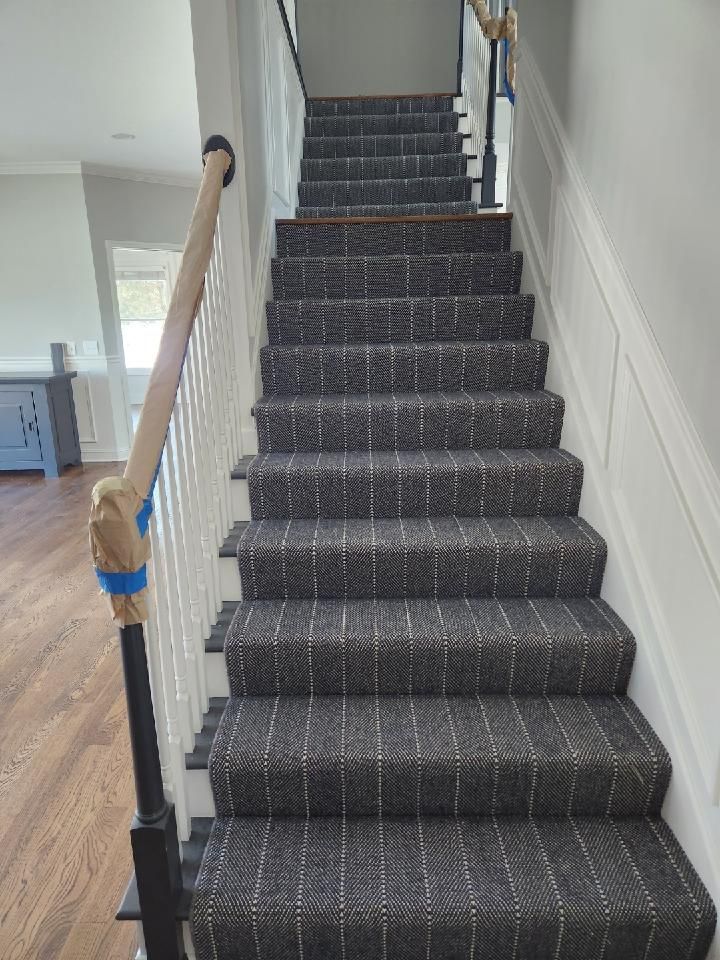 Charcoal wool carpet with thin stripe pattern installed on staircase with metal nosing and white painted walls.