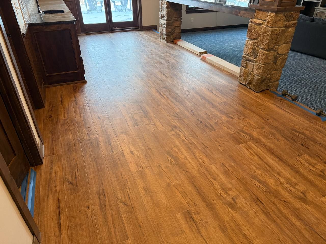 Luxury vinyl plank flooring in warm brown tones installed in an entryway with transitions to adjacent spaces.