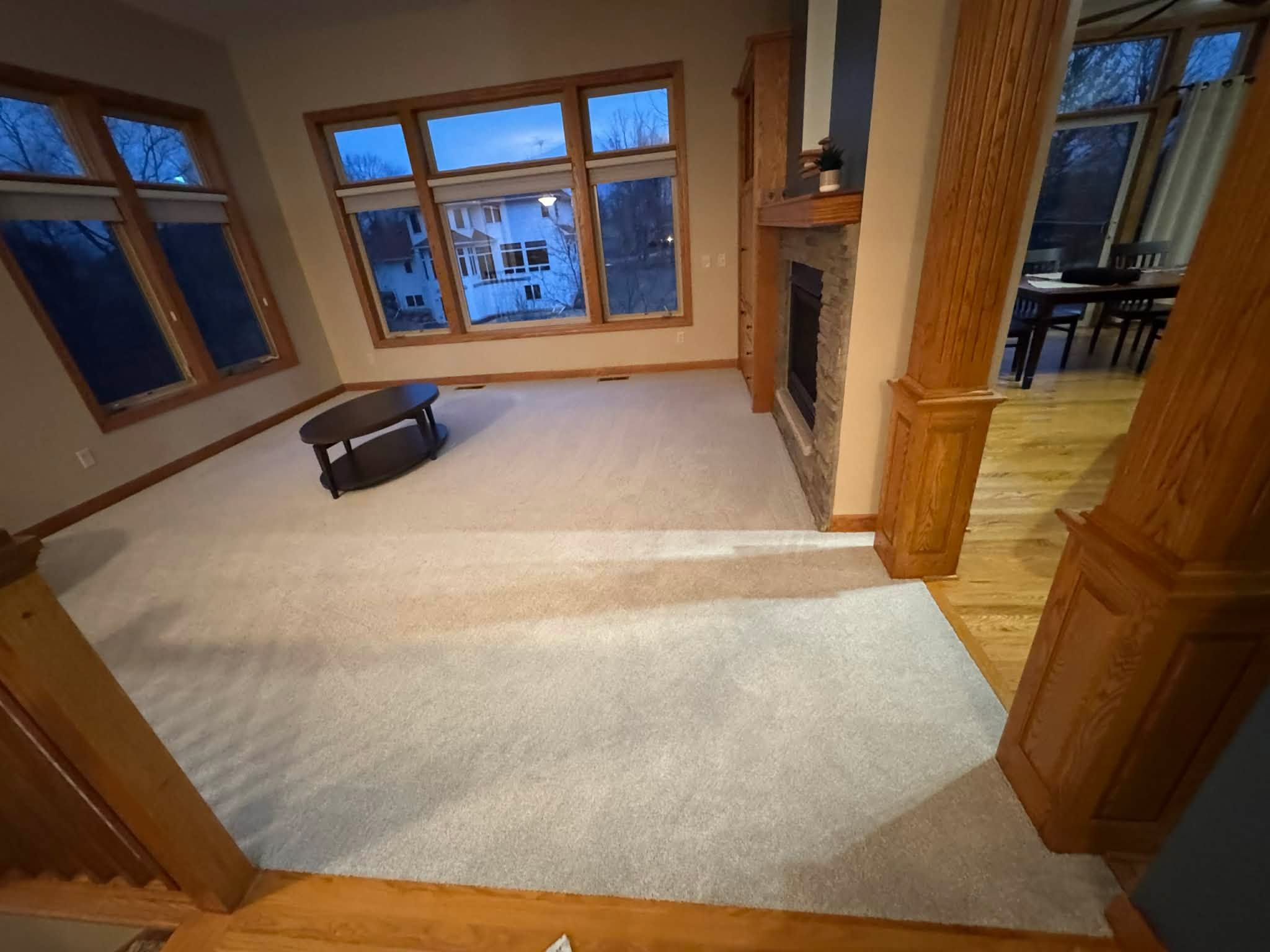 Newly installed light beige carpet in living room with fireplace and wood trim.