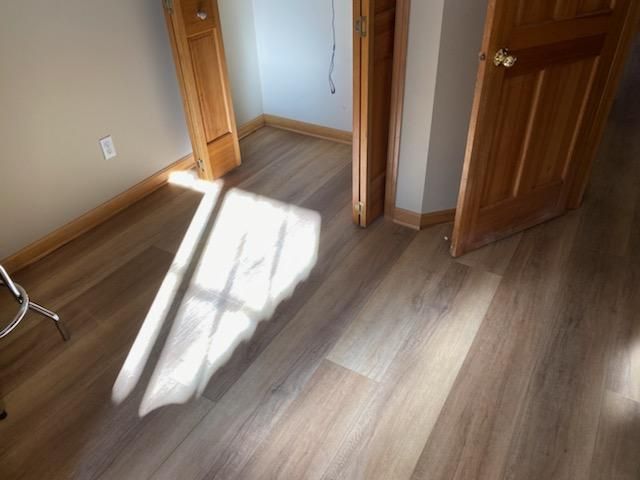 Hallway with medium-tone wood-grain LVP plank flooring and wooden door frames.