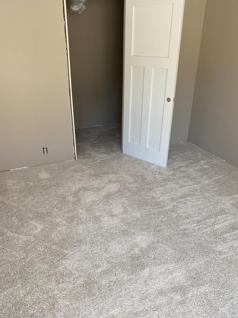 Newly installed light gray carpet in a bedroom with white doors and beige walls.