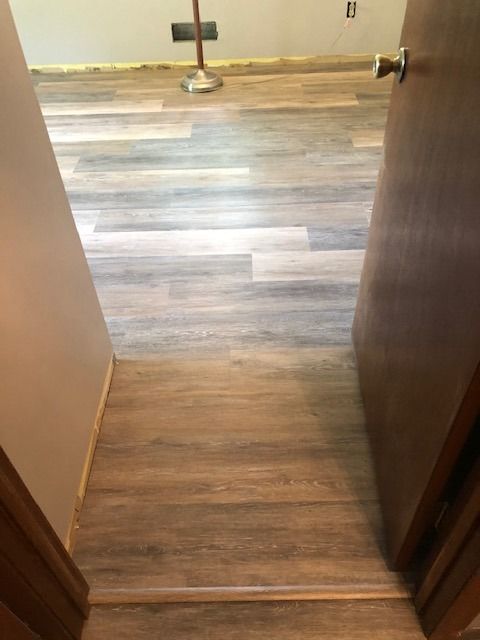 Bathroom with LVP plank flooring in mixed gray and brown tones installed in doorway transition.