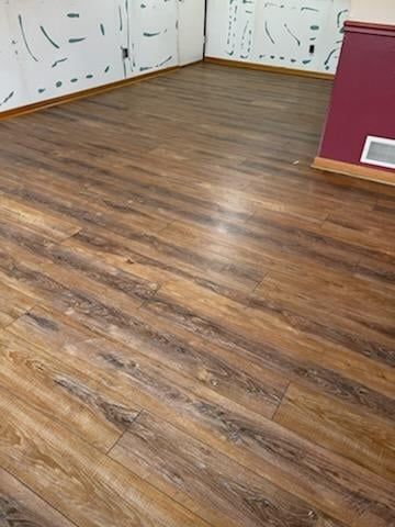 Luxury vinyl plank flooring with wood grain texture installed in a room with white walls and burgundy trim.
