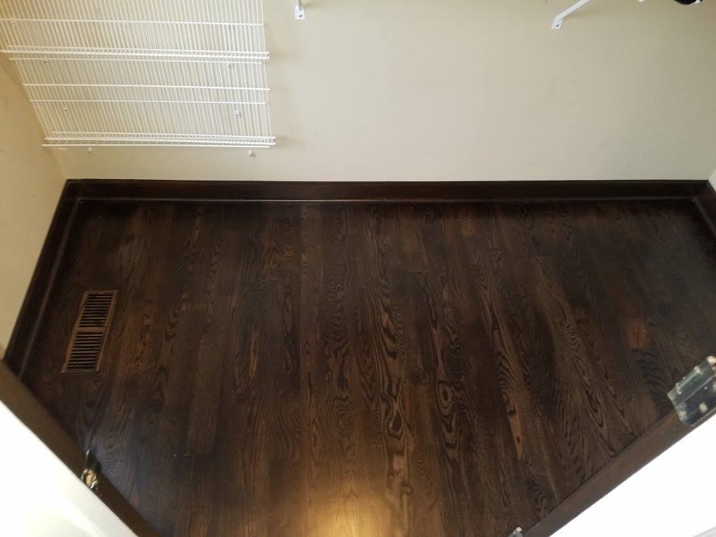Dark stained red oak hardwood plank flooring in a basement with a ceiling vent visible.