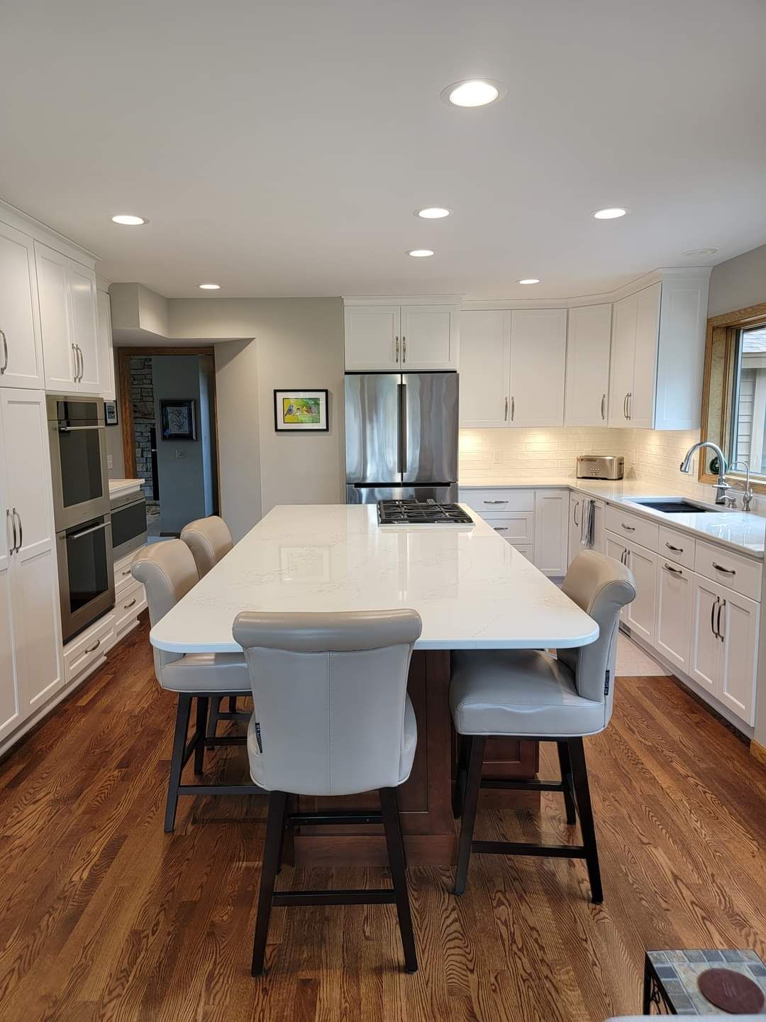 Medium-toned hardwood plank flooring in a kitchen with white cabinetry and a center island.
