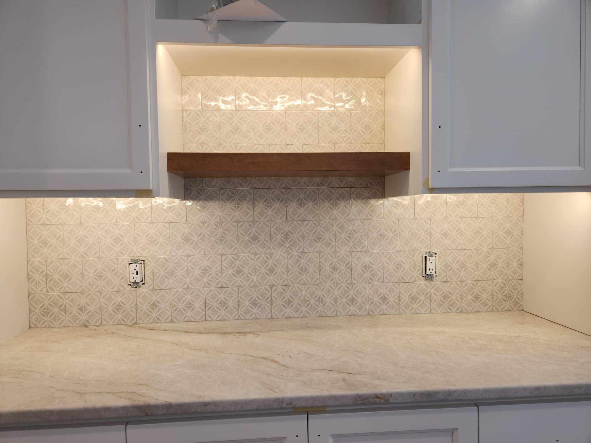 Kitchen backsplash with cream geometric tile pattern above marble countertop.