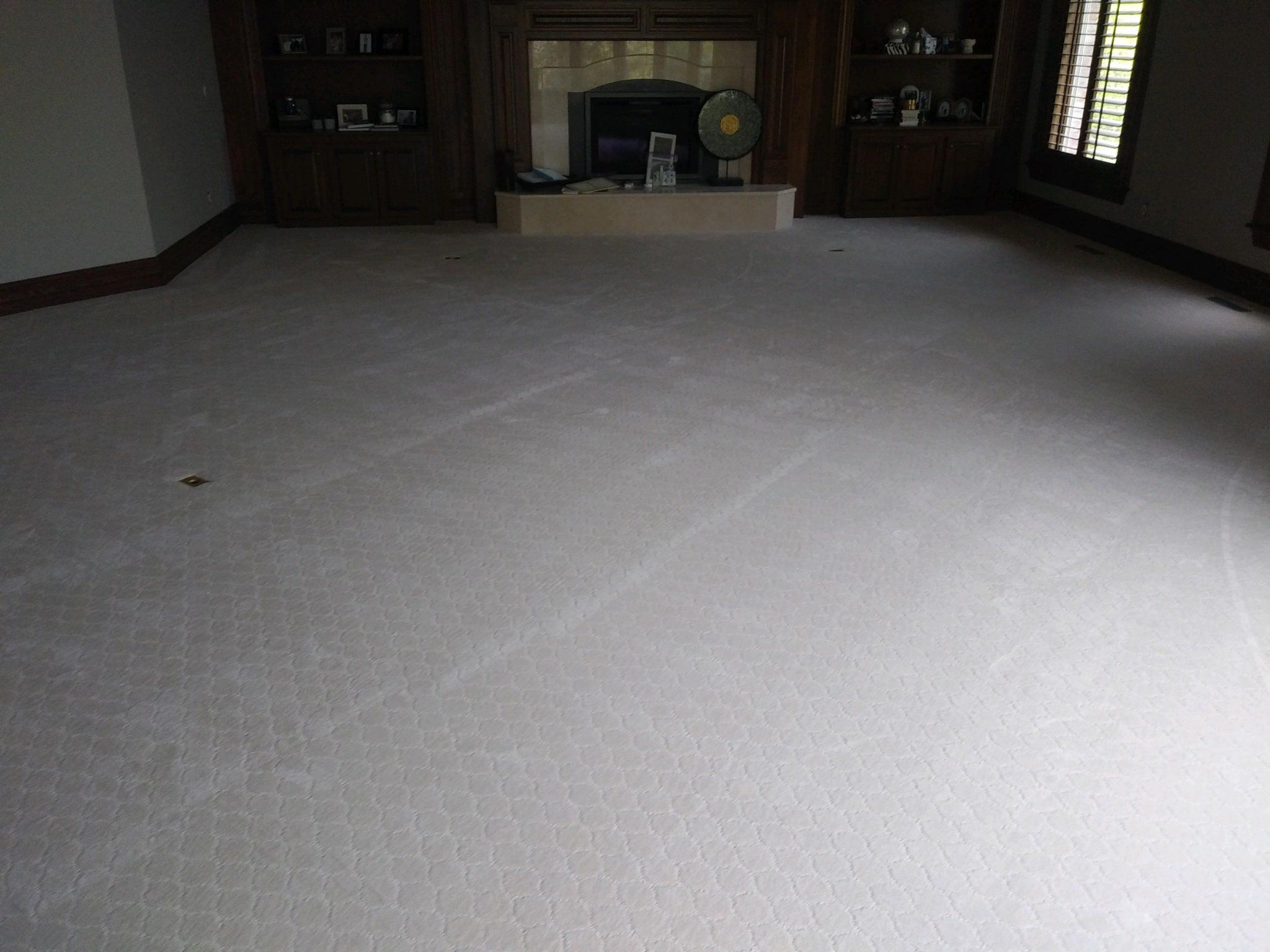 Empty living room with light gray carpet and built-in cabinetry with fireplace.