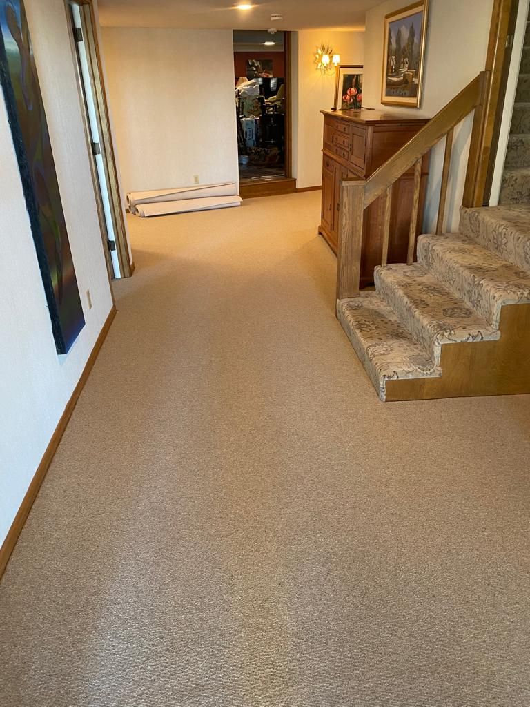 Hallway with tan wool carpet and wooden staircase with patterned runner on right side.