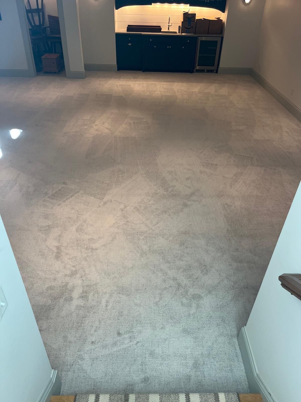 Gray and brown carpet installed in a kitchen with white walls and dark cabinets in the background.