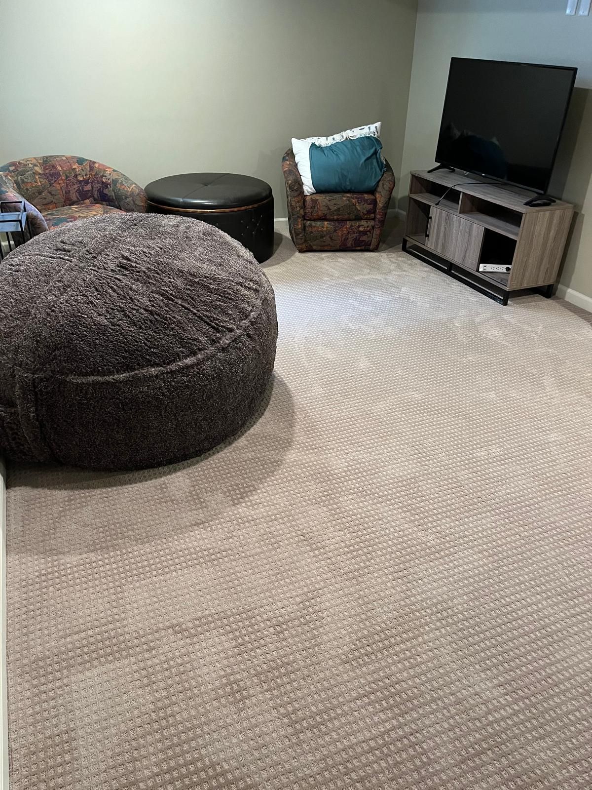 Light beige textured carpet installed in a finished basement with furniture and entertainment setup.