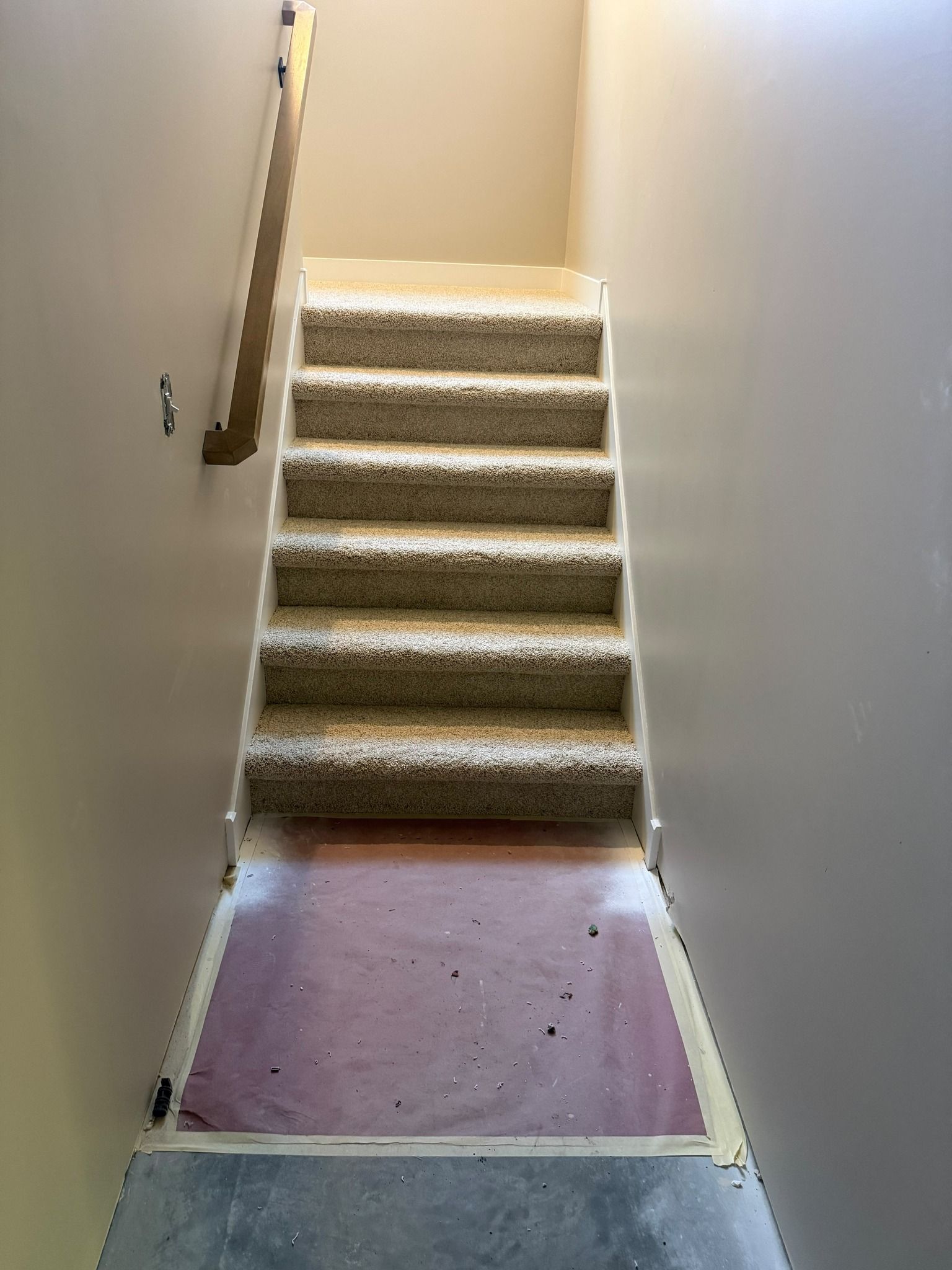Carpeted staircase with tan runner and white trim during installation in a residential home.