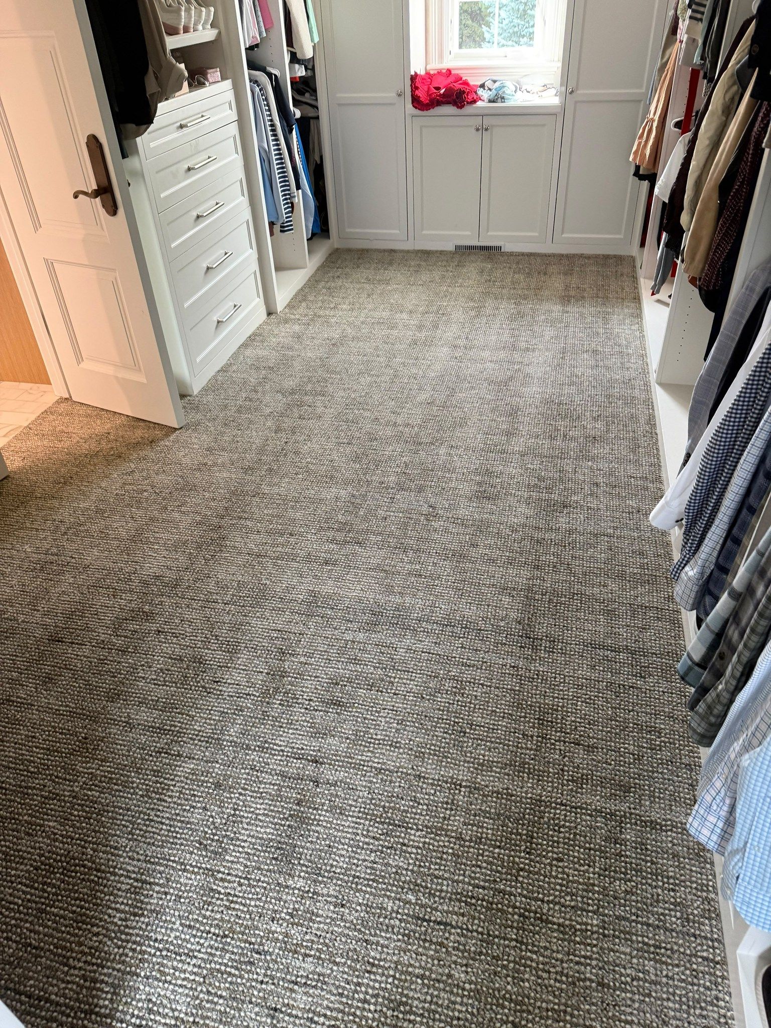 Gray wool carpet installed in a bedroom closet with built-in cabinetry and clothing racks.