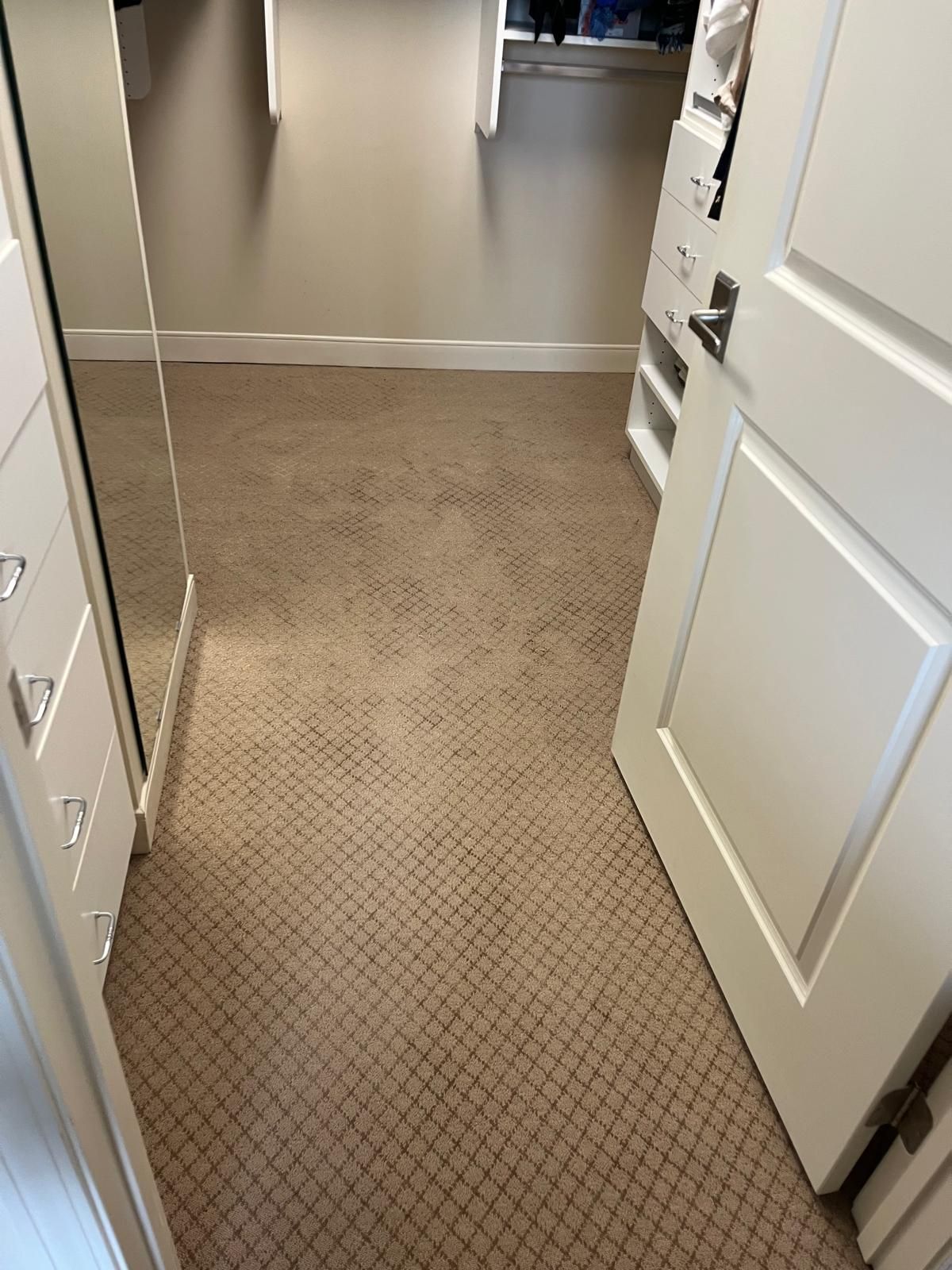 Beige carpet with geometric texture installed in kitchen with white cabinetry and metal transition to adjacent hard flooring.