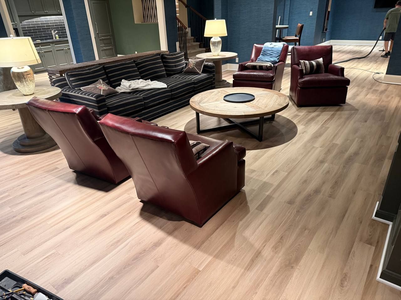 Light tan wood-look LVP planks installed in living room with burgundy leather furniture and blue accent walls.