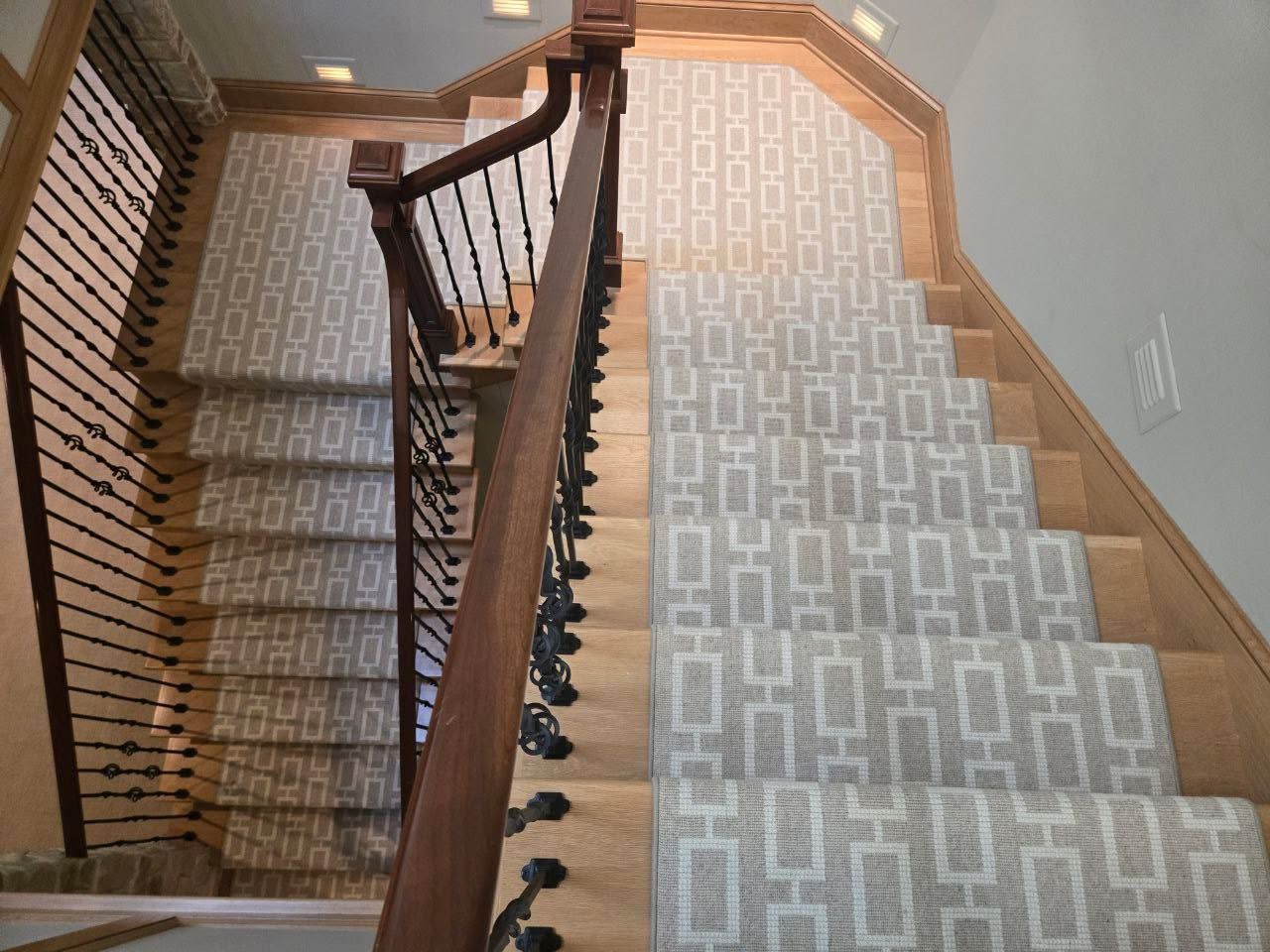 Staircase with geometric patterned wool carpet runner and wood-framed borders.