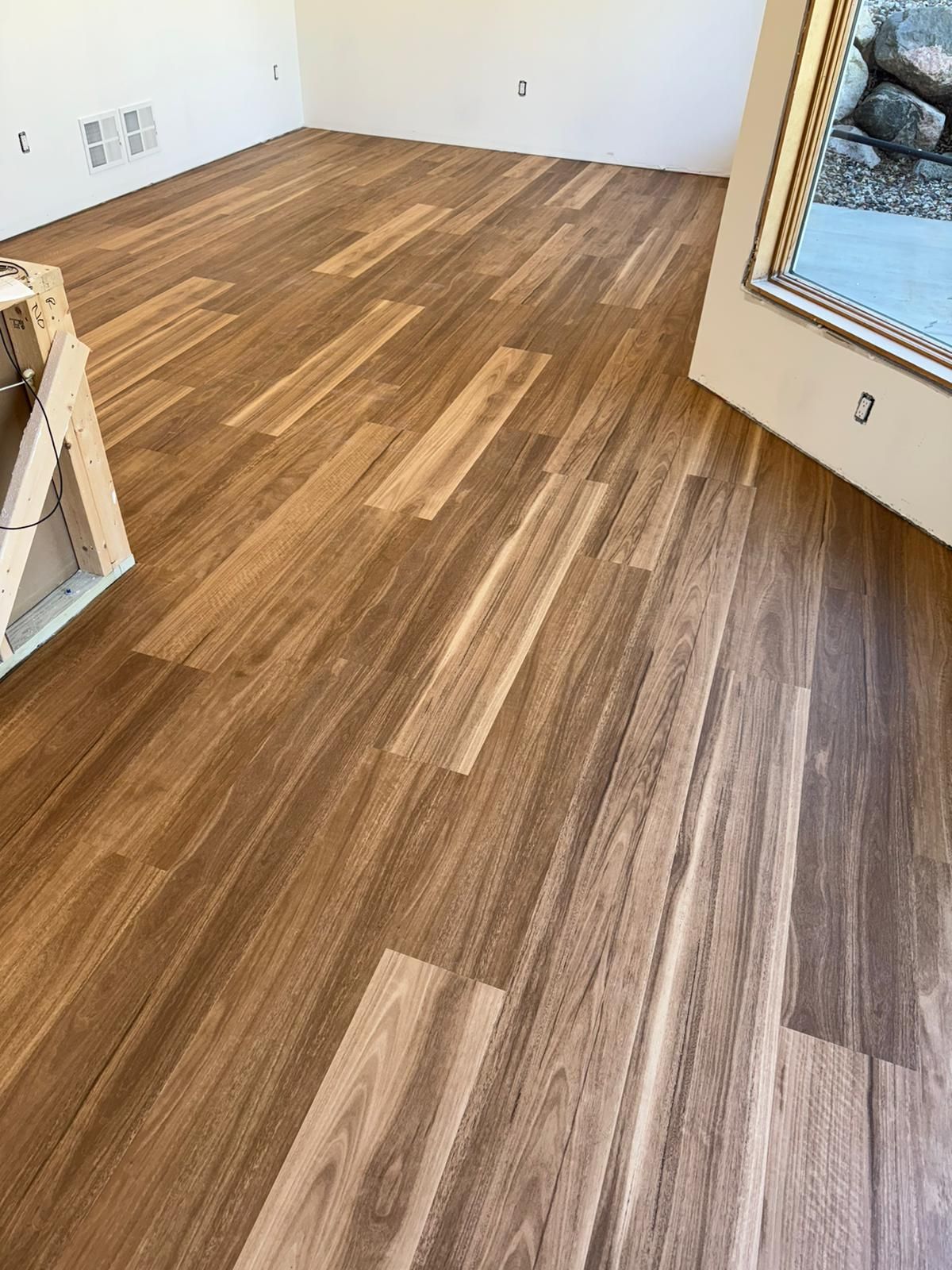 Newly installed luxury vinyl plank flooring in mixed brown and gray tones laid in a staggered plank pattern in a bedroom.