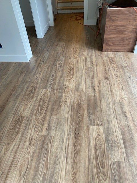 Luxury vinyl plank flooring with wood grain pattern installed in a hallway with white trim and doorway.