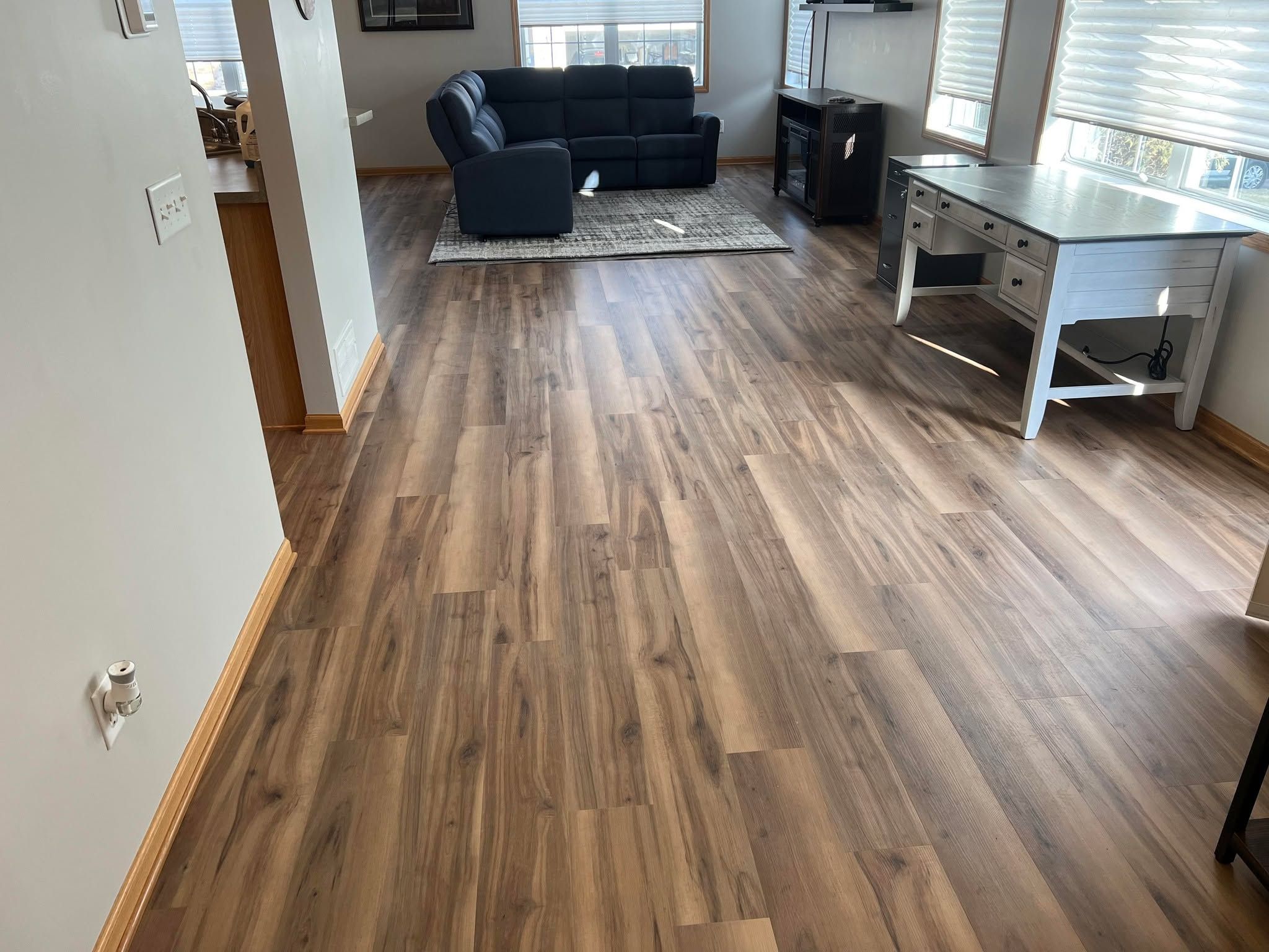 Living room with medium-toned wood-look LVP planks installed in an open floor plan.
