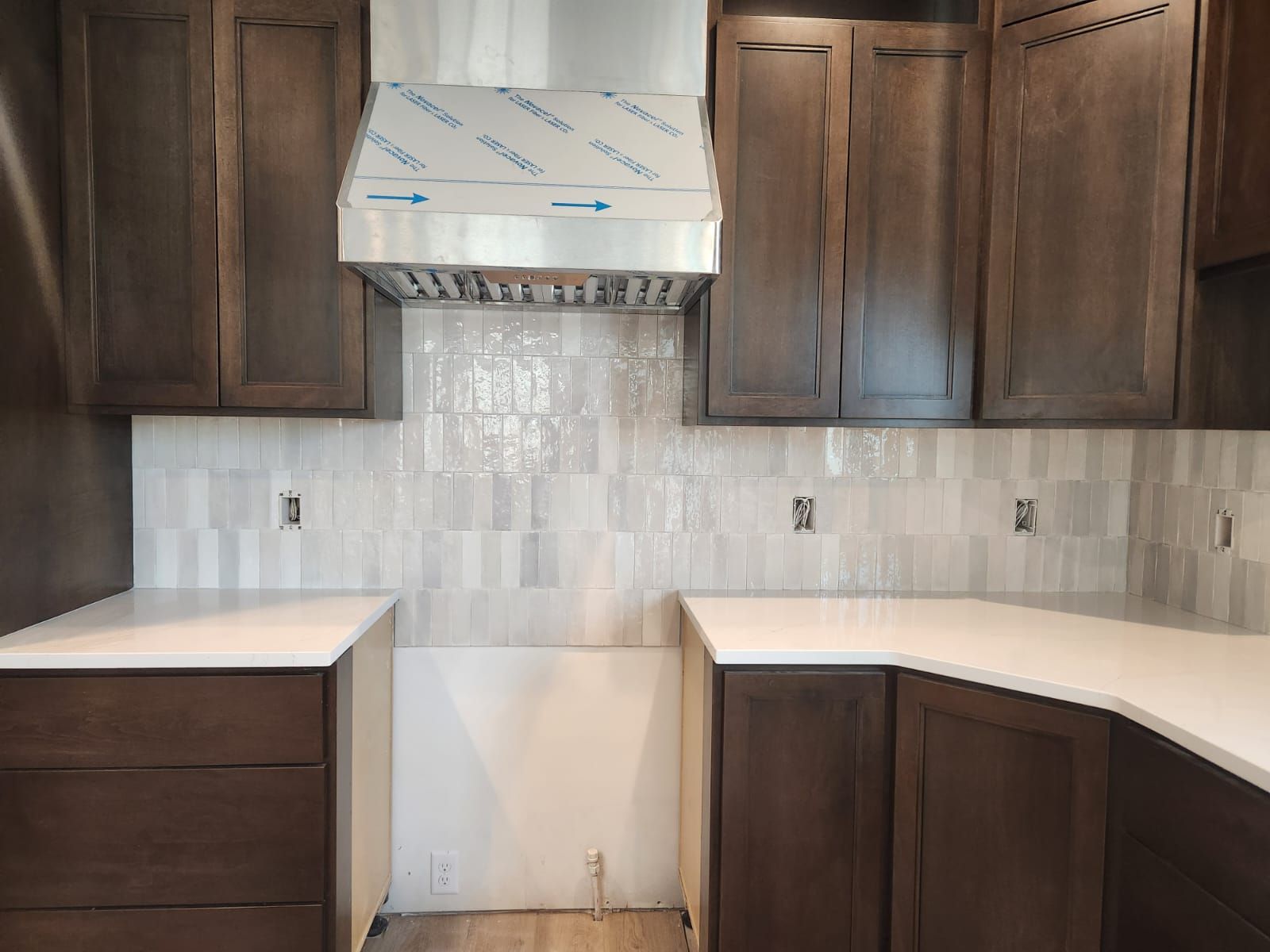 Kitchen backsplash and bar splash installed with white subway tile behind dark brown cabinetry.