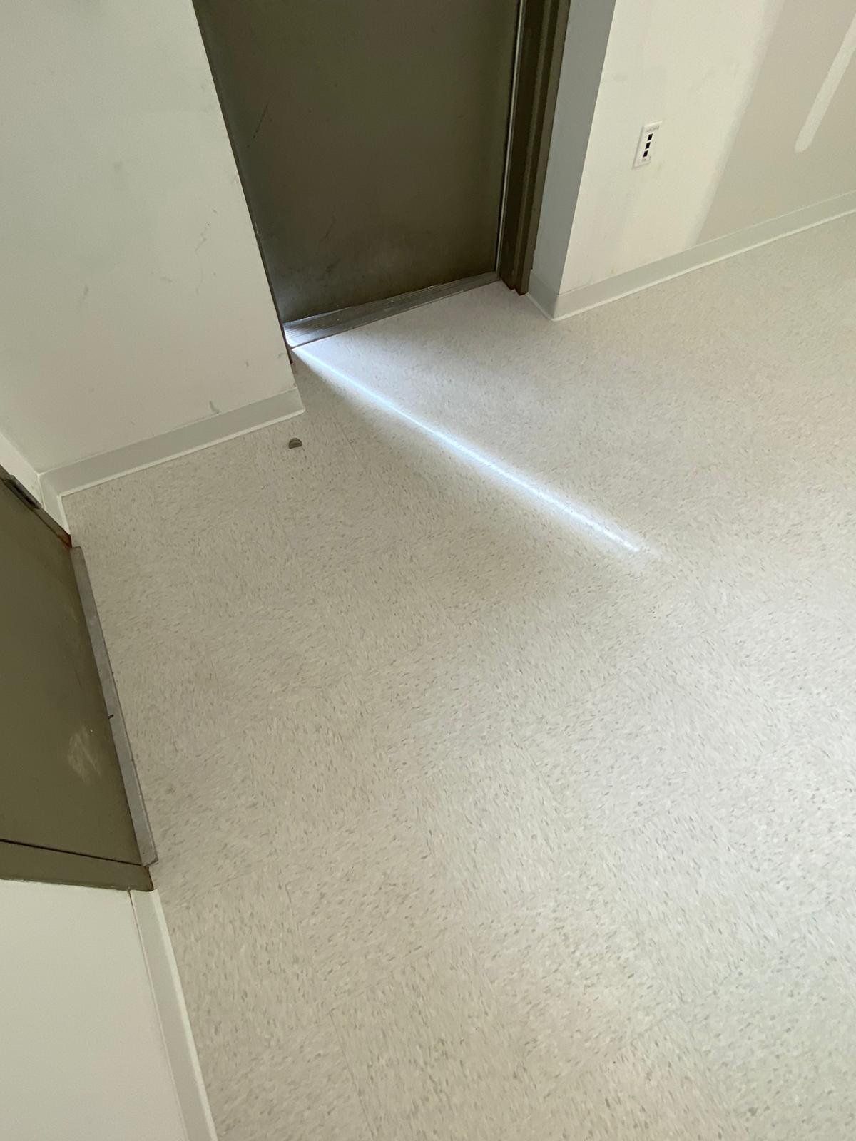 Light beige LVP flooring in entryway with doorway to dark room visible.