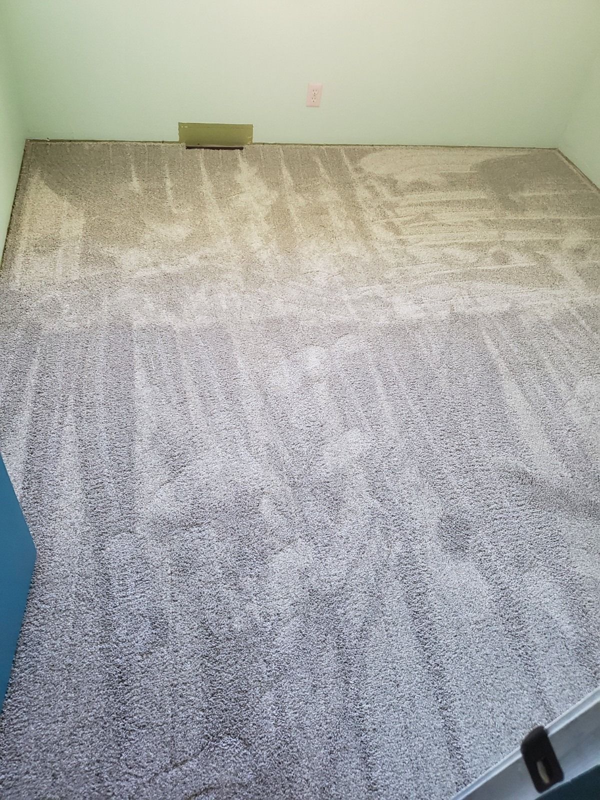 Newly installed gray and beige textured carpet in a bedroom with light green walls.