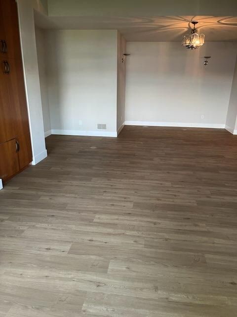 Light tan and brown luxury vinyl plank flooring in an empty living room with white walls and wooden closet doors.